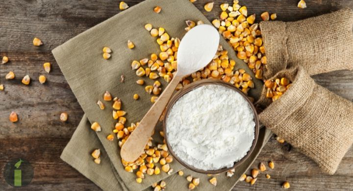 a bowl of flour and spoon with corn kernels
